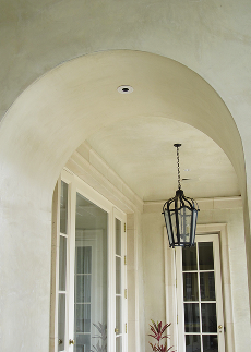 Cream-colored hallway with arched ceiling, pendant light fixture, and glass doors on either side