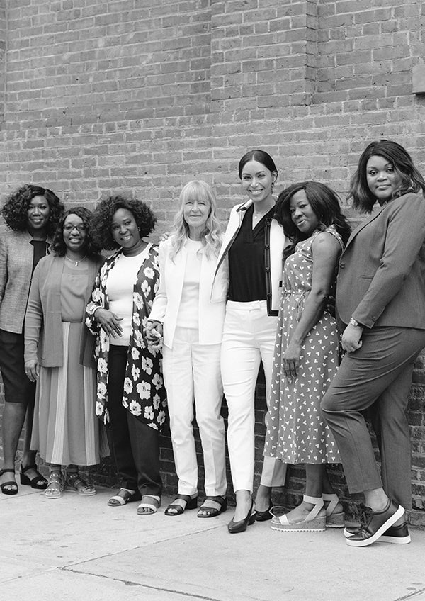 Group of women in Anne Klein apparel standing together against a brick wall