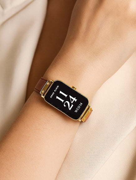 Gold smartwatch displaying time on a person wrist
