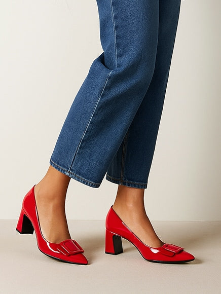 Woman wearing red heels and blue cropped jeans against a beige background
