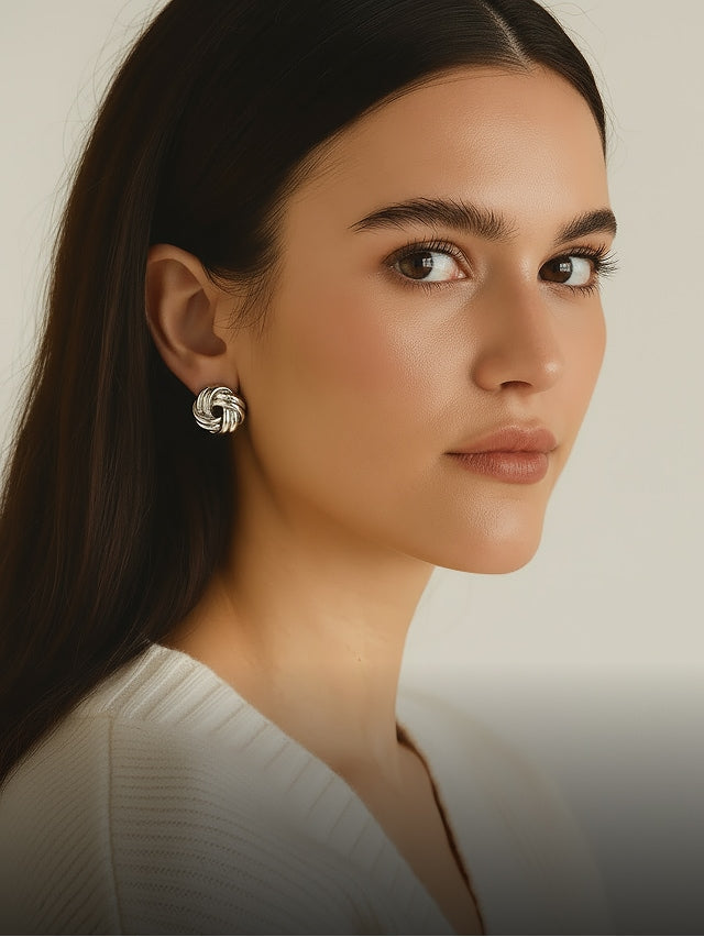 Woman with neat hairstyle wearing large round earrings and a white top
