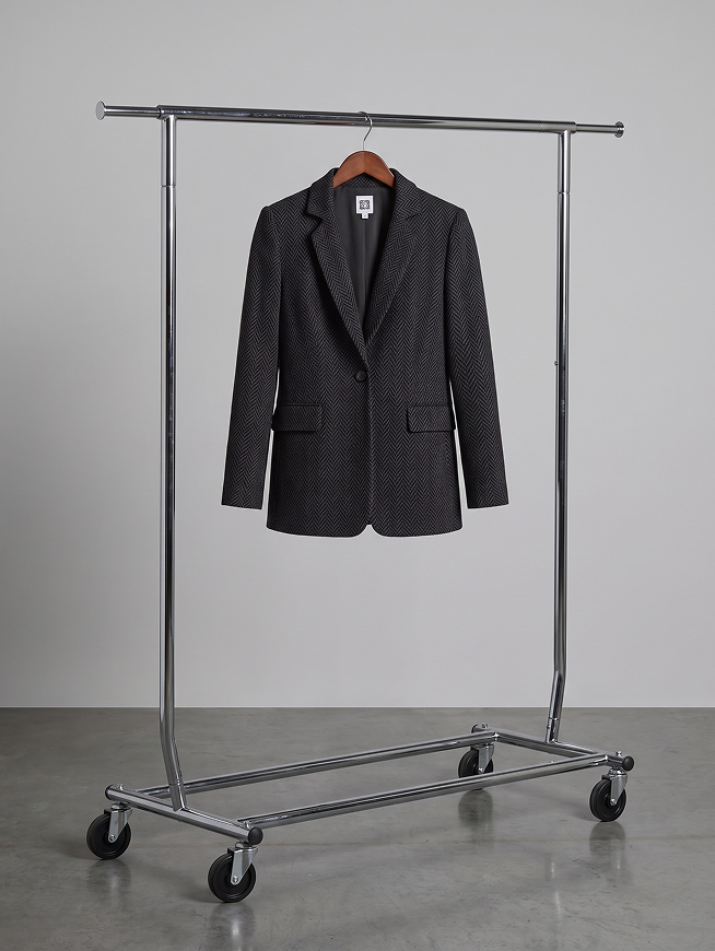 Black textured blazer on wooden hanger, displayed on rolling garment rack against gray background