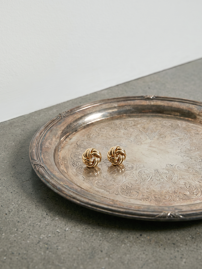 Gold knot stud earrings on silver tray, link to gold knot stud earrings